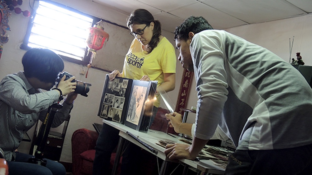 魏時煜（左）與助手 Anna Walter 在何秋蘭家裏翻拍相片